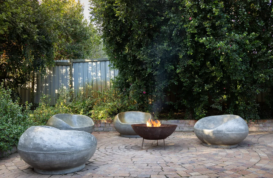 A gravel courtyard with stone seating around a fire bowl